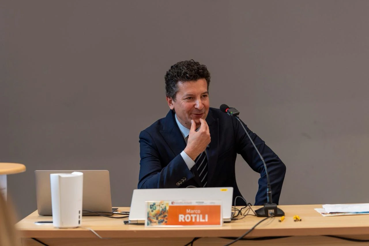 Marco Rotili al tavolo di un incontro, davanti al microfono